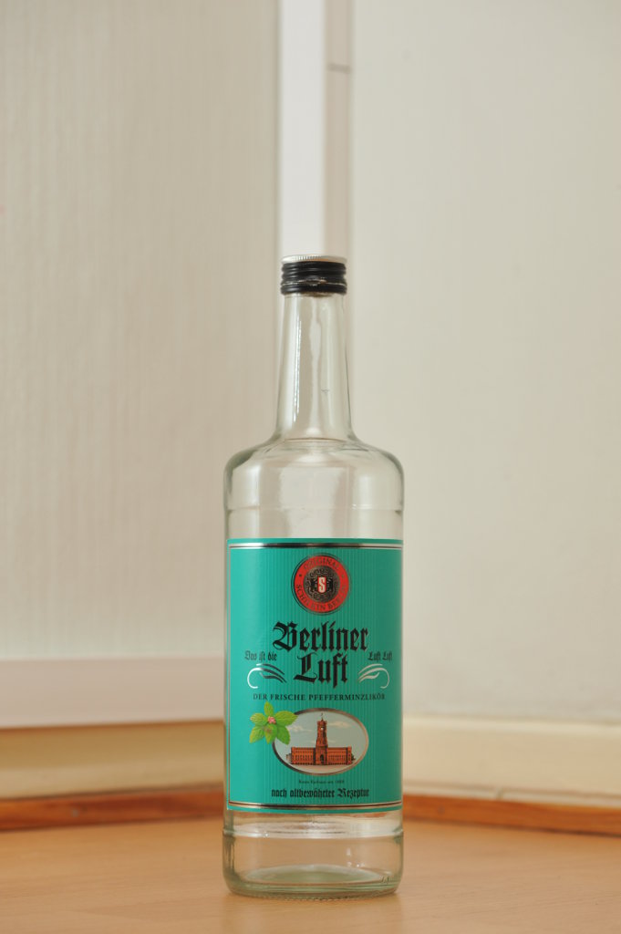 Tyhjä Berliner Luft -liköörin kirkas 1,0 litran pullo puunvärisellä lattialla.