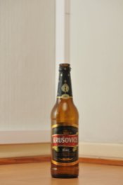 Tyhjä Krušovice-oluen 0,5 litran ruskea lasipullo puunvärisellä lattialla.