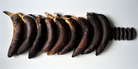 Tummuneita banaaneja vierekkäin suklaapäällysteisten banaanivaahtokaramellien vieressä.