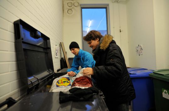 Onni Tonkija ja Roope Salminen tutkivat roskapussien sisältöä jätehuoneessa.
